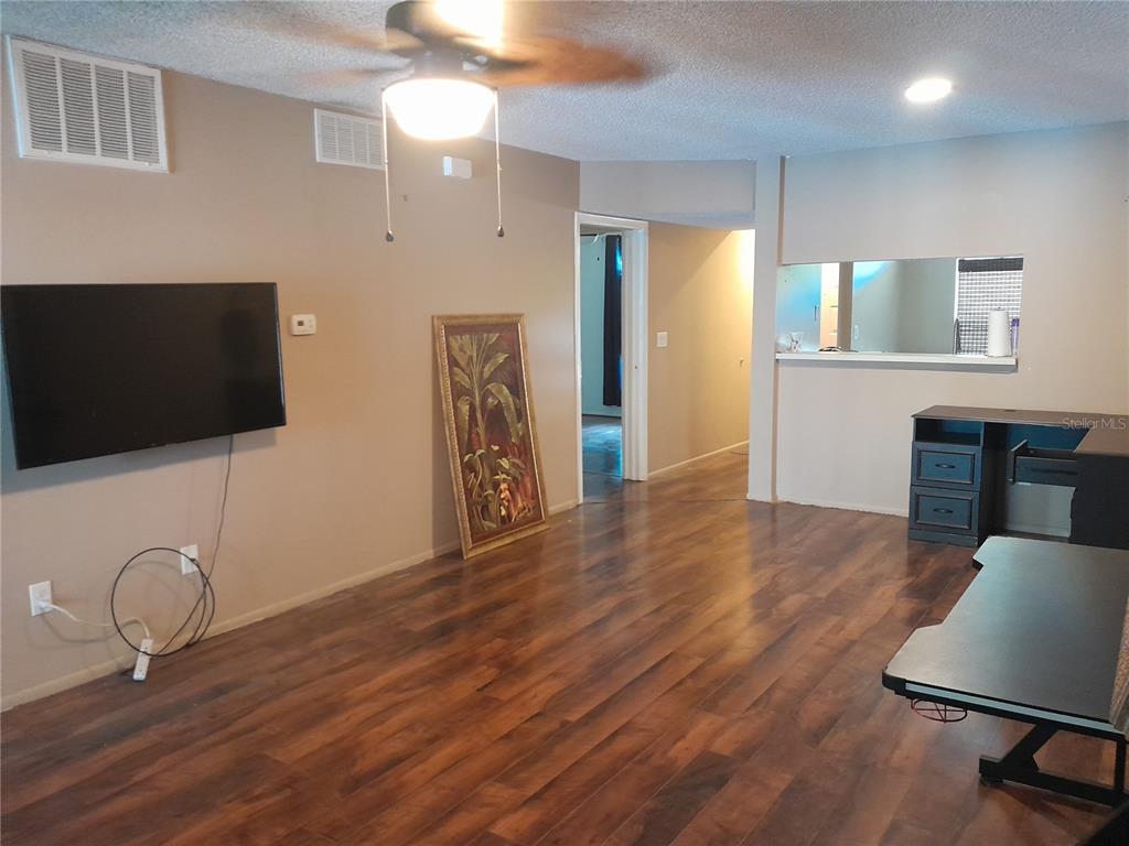 A living room with wood-look flooring, a corner fireplace, and a sliding glass door — 25210 NORTHLAKE DRIVE UNIT 210, SANFORD, FL