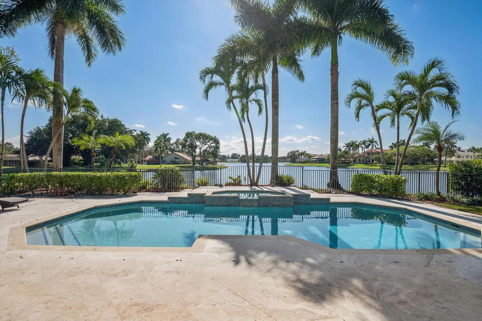 A swimming pool and hot tub overlook a lake surrounded by palm trees and houses — 7600 Hyannis Lane, Parkland FL 33067, PARKLAND, FL