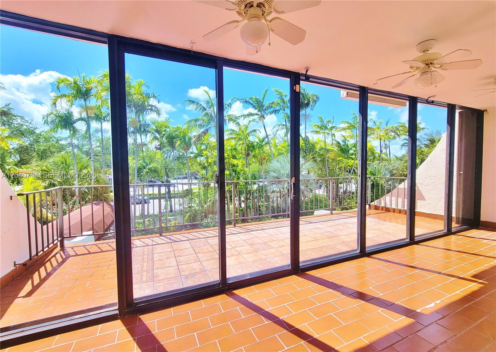 An empty room features light-colored tile flooring, white walls, and a sliding glass door — 77 Crandon Blvd # 2B, Key Biscayne FL 33149, KEY BISCAYNE, FL