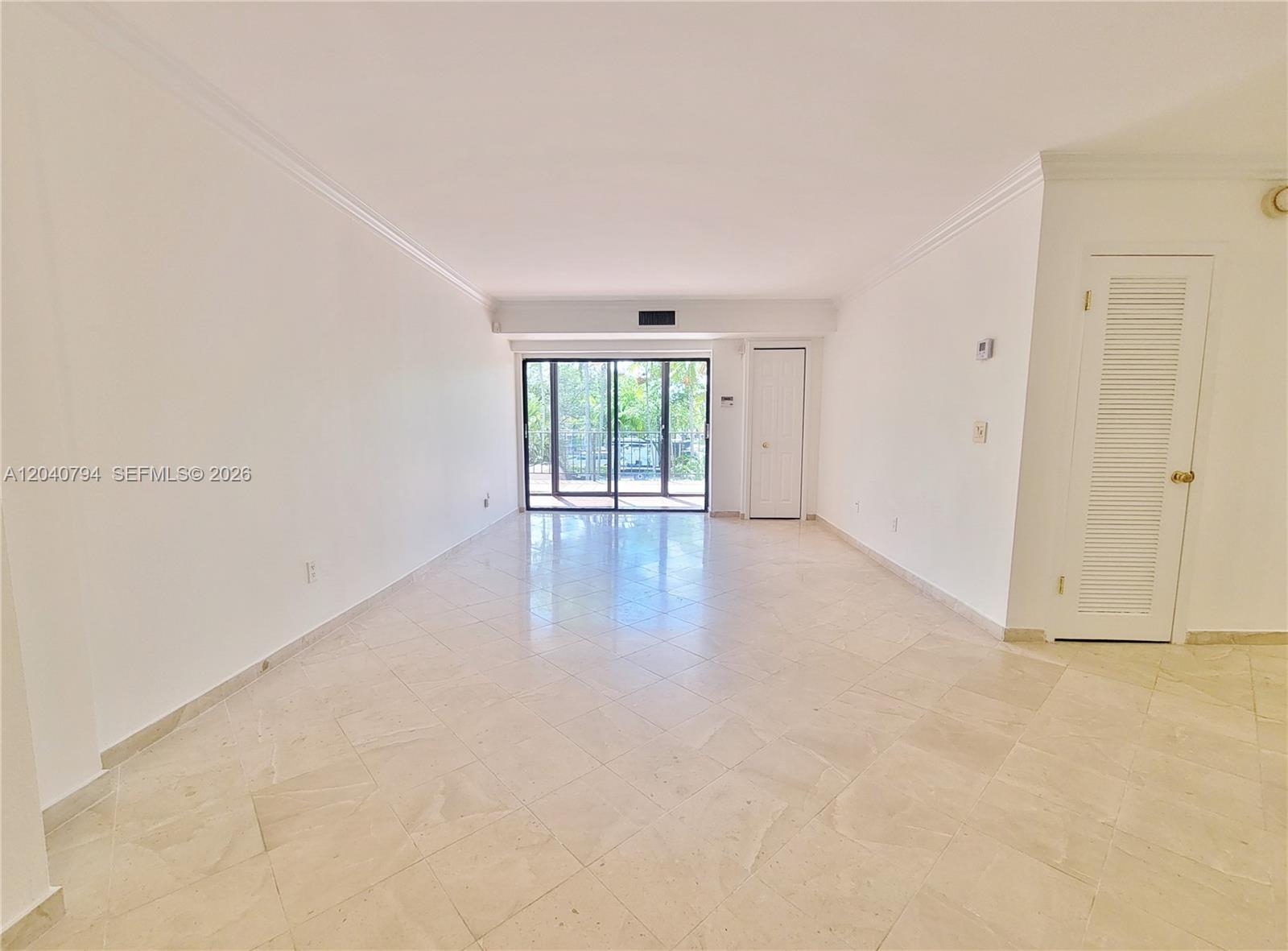 An empty room features white walls, tile flooring, and a sliding glass door to a balcony — 77 Crandon Blvd # 2B, Key Biscayne FL 33149, KEY BISCAYNE, FL