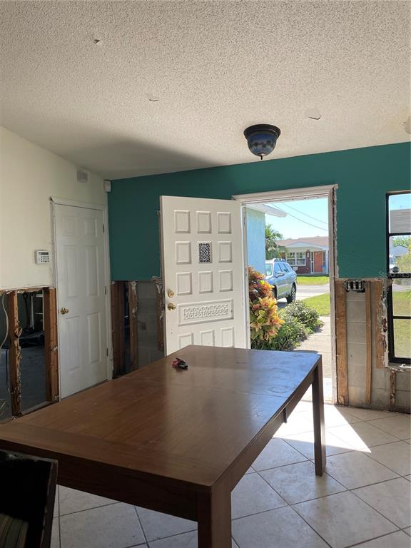 An unfinished room with exposed wall studs, a wooden table, and an open front door — 13612 FRANCES AVENUE, HUDSON, FL