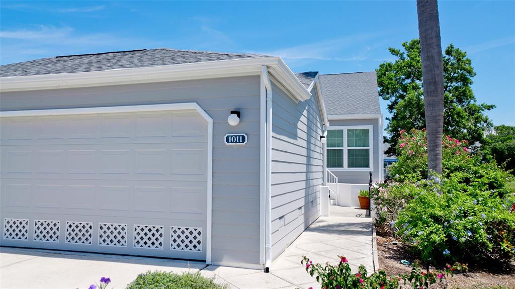 A light gray house exterior features a garage with a white door and address plaque — 1011 IBIS COURT, BRADENTON, FL