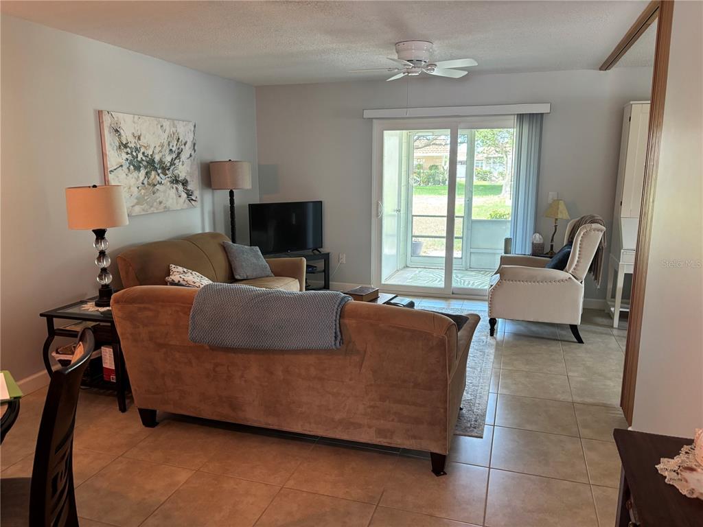 A living room features tile flooring, a tan sofa, an armchair, and sliding glass doors — 668 PARK CIRCLE, BRADENTON, FL