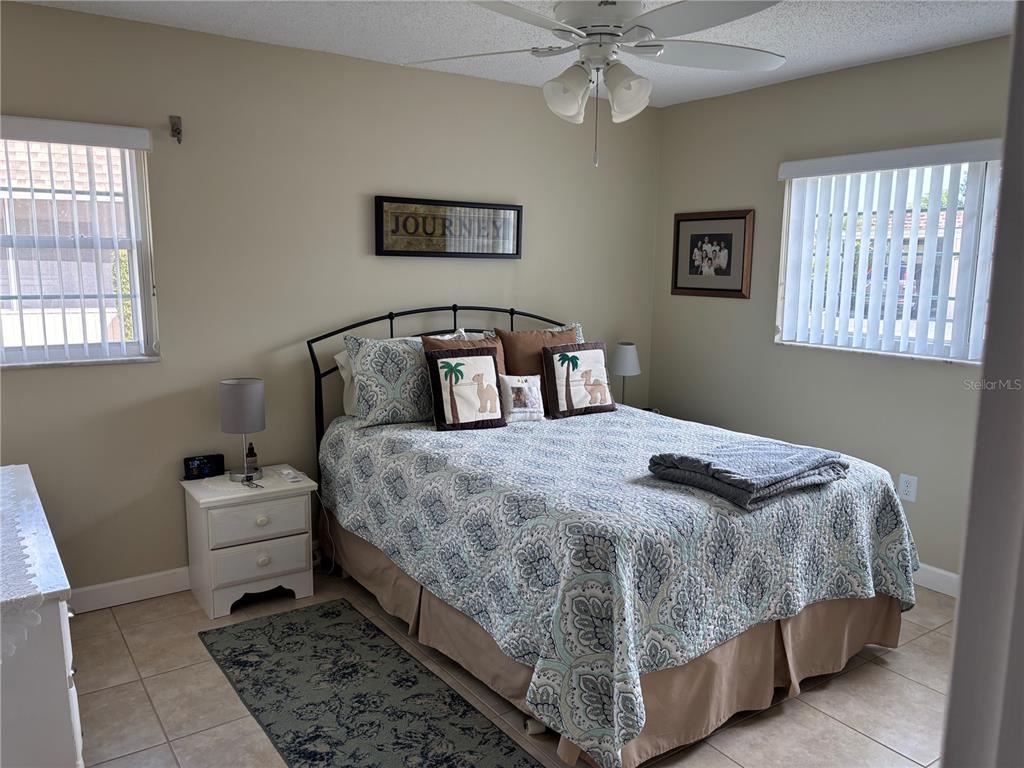 A bedroom features a bed with a patterned quilt, two nightstands, and two windows — 668 PARK CIRCLE, BRADENTON, FL