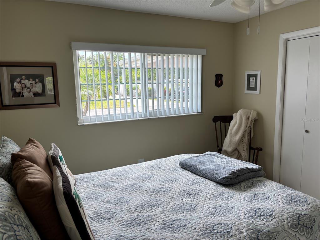 A bedroom features a bed with a patterned quilt, a window with blinds, and a closet — 668 PARK CIRCLE, BRADENTON, FL