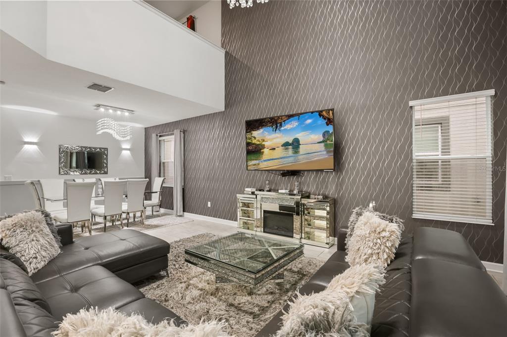 A living room with a gray sectional, mirrored coffee table, and a textured accent wall — 621 DROP SHOT DRIVE, DAVENPORT, FL
