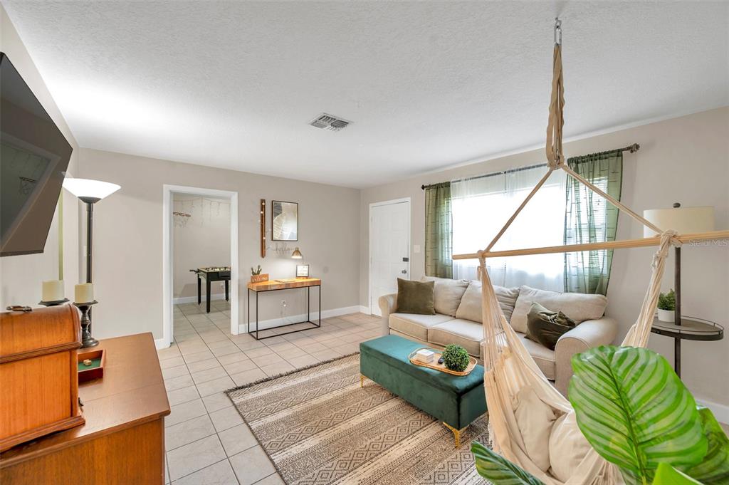 A living room features tile floors, a beige sofa, a hanging chair, and a rug — 3371 N BAY AVENUE, CRYSTAL RIVER, FL