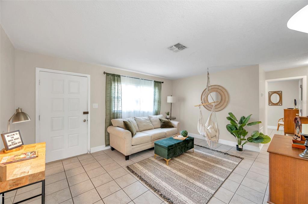 A living room features a beige sofa, a green ottoman, and a hanging chair — 3371 N BAY AVENUE, CRYSTAL RIVER, FL
