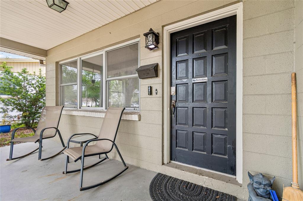 A covered porch features two rocking chairs, a black front door, and a broom — 621 E DAVIS BOULEVARD, TAMPA, FL