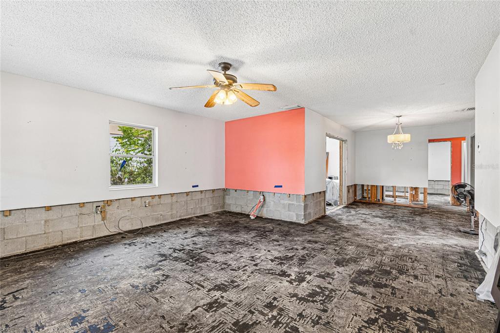 An unfinished room with exposed concrete block walls, a popcorn ceiling, and bare subflooring — 621 E DAVIS BOULEVARD, TAMPA, FL