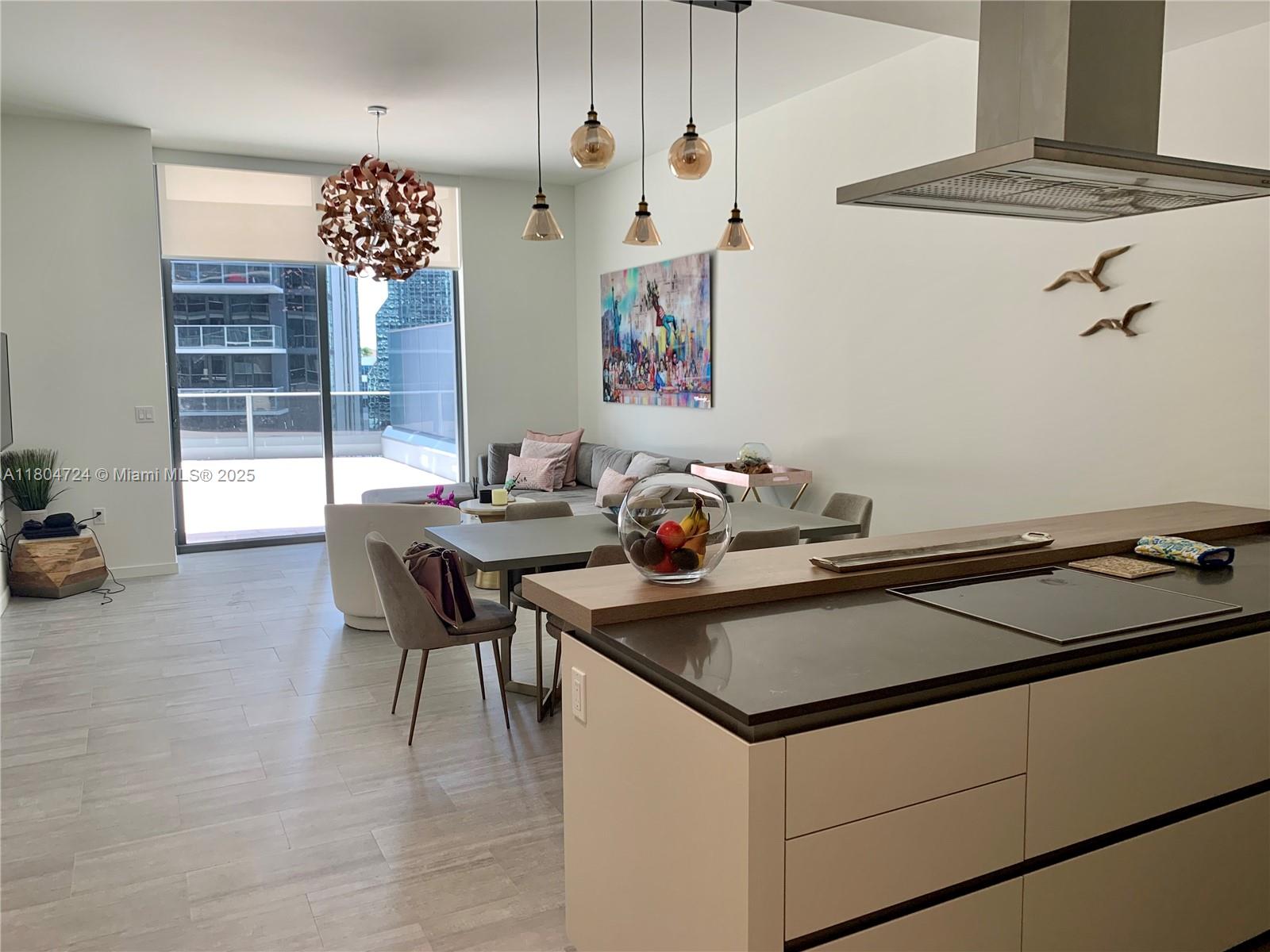 A modern open-concept kitchen and living area features a dining table, sofa, and balcony access — 1000 Brickell Plz # 1805, Miami FL 33131, MIAMI, FL