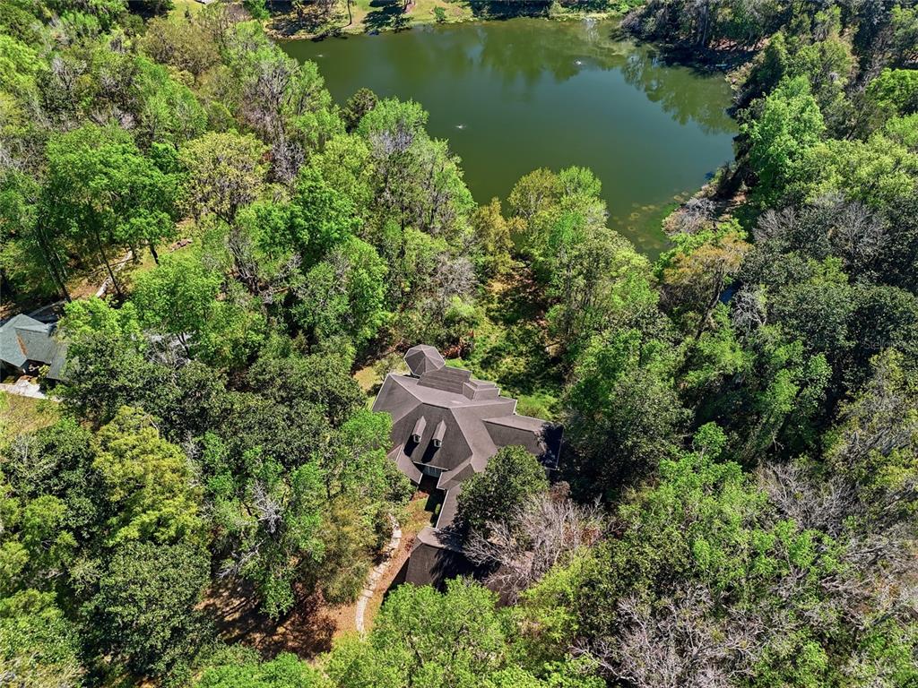 An aerial view shows a house with a dark roof nestled in a wooded area — 9510 NW 59TH LANE, GAINESVILLE, FL