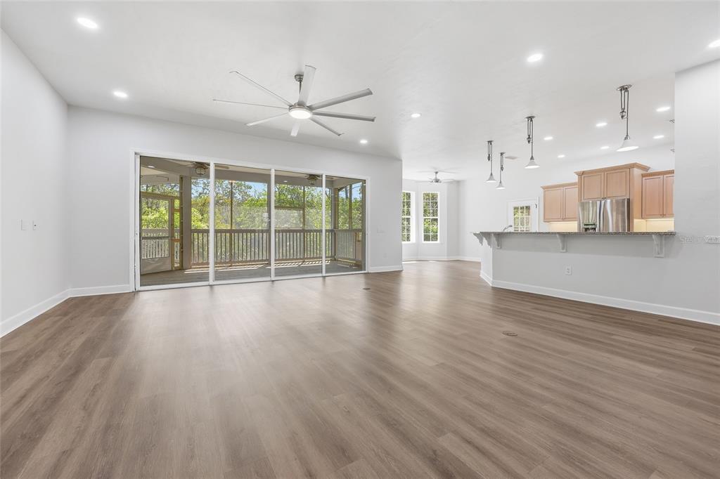 A bright open-concept living area with wood-look flooring, a ceiling fan, and sliding glass doors — 9510 NW 59TH LANE, GAINESVILLE, FL