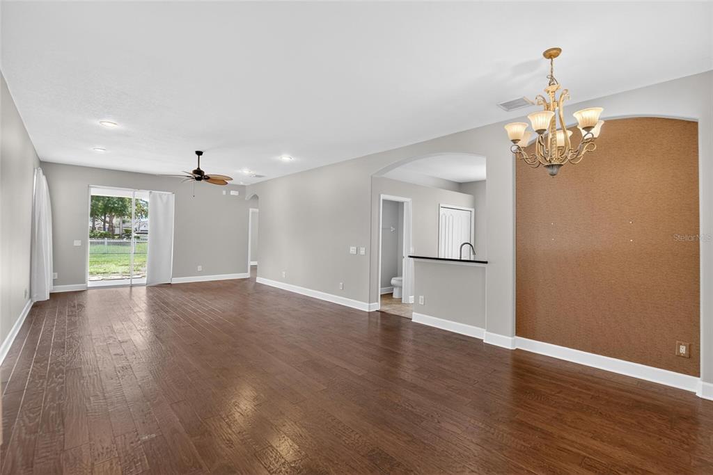 An open-concept living area features dark wood flooring, a cork-accented wall, and a chandelier — 21040 GREEN WING COURT, LAND O LAKES, FL