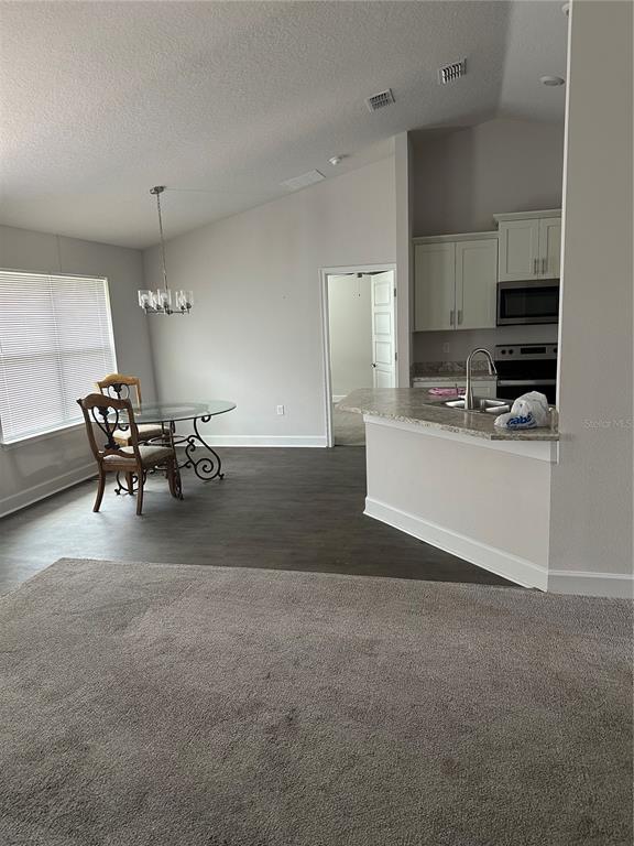 A dining area with a glass table and chairs sits adjacent to a kitchen island — 14 PRIMROSE LANE, PALM COAST, FL
