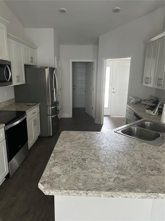 A kitchen features white cabinets, stainless steel appliances, and a light-colored stone countertop — 14 PRIMROSE LANE, PALM COAST, FL