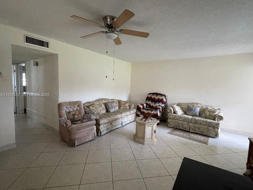 A living room features tile flooring, a ceiling fan, and several pieces of upholstered furniture — 5300 Washington St # S111, Hollywood FL 33021, HOLLYWOOD, FL