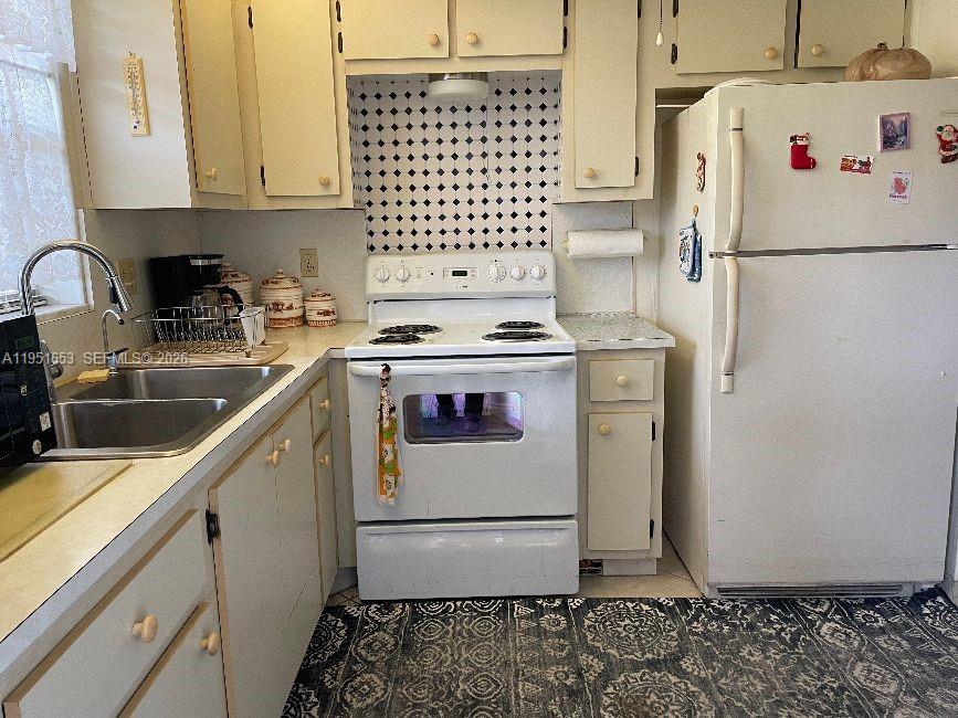 A kitchen features white cabinets, a white stove, a double sink, and a patterned rug — 5300 Washington St # S111, Hollywood FL 33021, HOLLYWOOD, FL