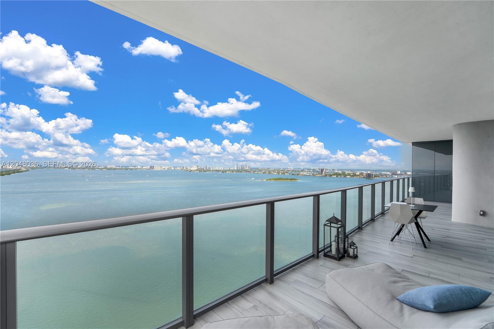A balcony with gray tile flooring overlooks a large body of water and city skyline — 3131 NE 7th Ave # 2706, Miami FL 33137, MIAMI, FL
