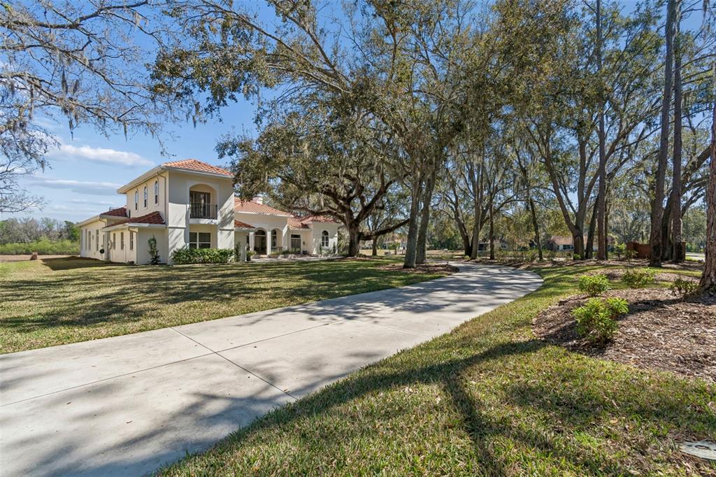 A two-story stucco house with a tile roof sits at the end of a driveway — 5212 GOLF LINKS BOULEVARD, ZEPHYRHILLS, FL