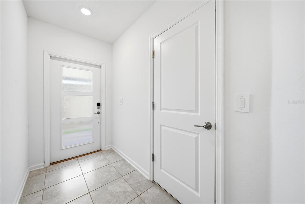 A bright entryway features white walls, a tiled floor, and two white doors — 8871 CABOT CLIFFS DRIVE UNIT 102, DAVENPORT, FL