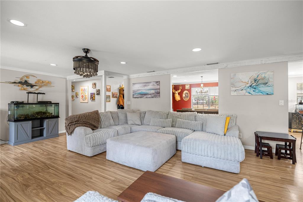 A living room features a large gray sectional sofa, wood-look flooring, and a fish tank — 5100 SE 44TH AVENUE ROAD, OCALA, FL