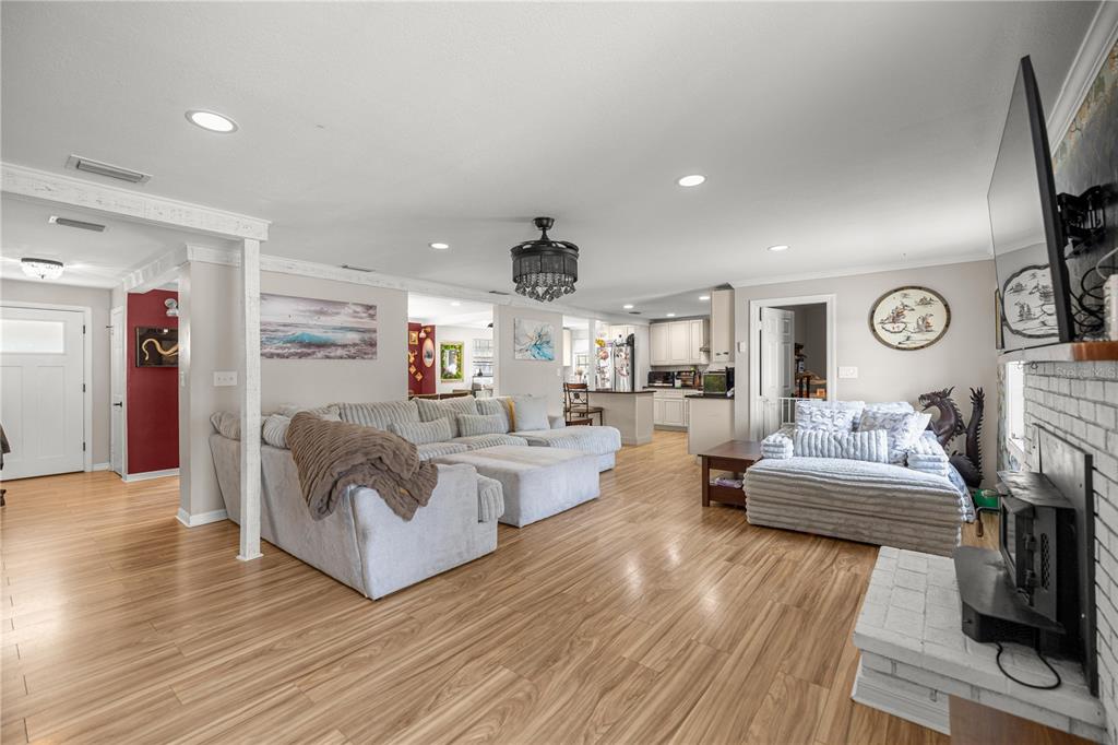 A spacious living room features light wood flooring, a large sectional sofa, and a fireplace — 5100 SE 44TH AVENUE ROAD, OCALA, FL