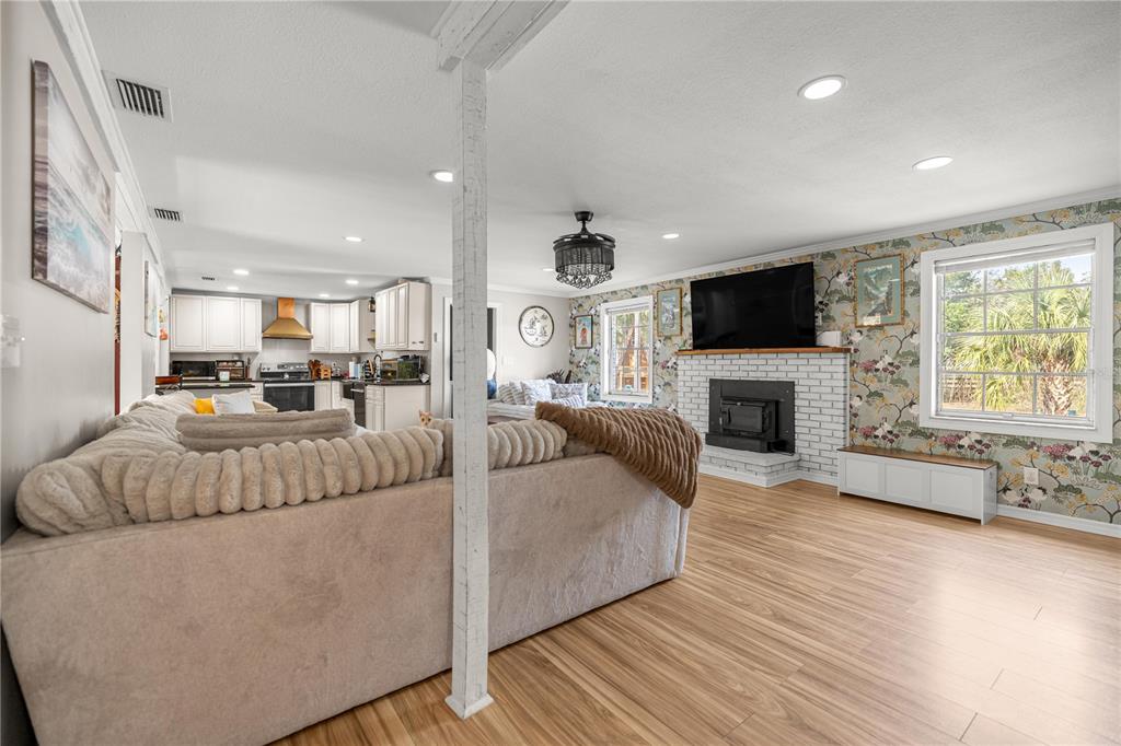 A living room with a brick fireplace, patterned wallpaper, and a large sectional sofa — 5100 SE 44TH AVENUE ROAD, OCALA, FL