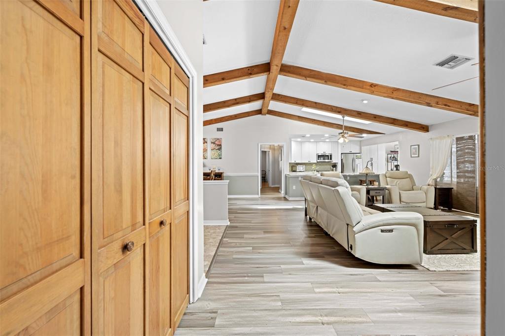 A view from a hallway into an open-concept living room with exposed wooden ceiling beams — 5 CHINKAPIN CIRCLE, HOMOSASSA, FL
