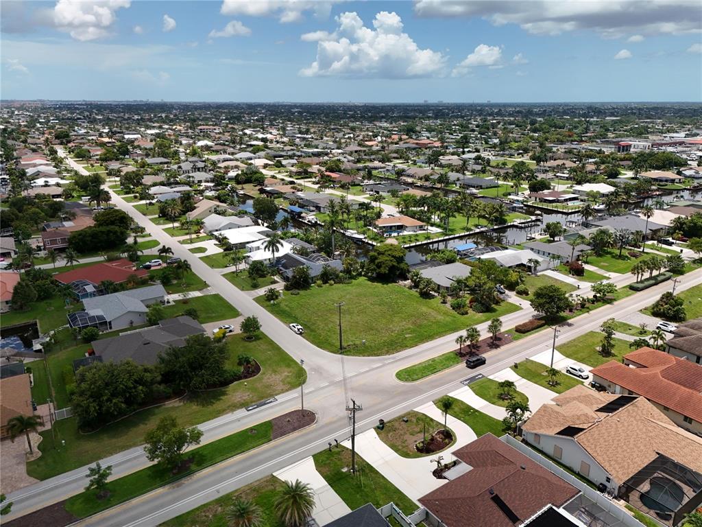 An aerial view shows a residential neighborhood with houses, a vacant lot, and canals — 2014 EVEREST PARKWAY, CAPE CORAL, FL