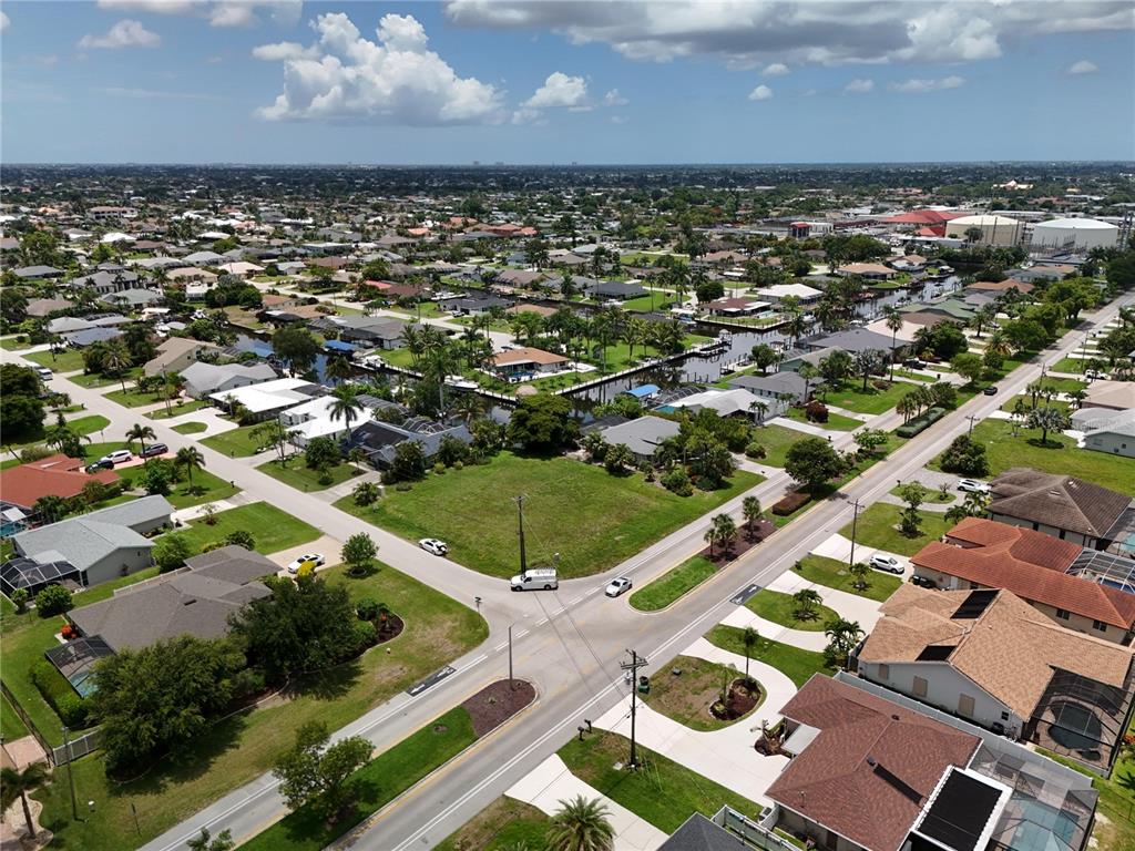 An aerial view shows a residential neighborhood with houses, a canal, and a vacant lot — 2014 EVEREST PARKWAY, CAPE CORAL, FL