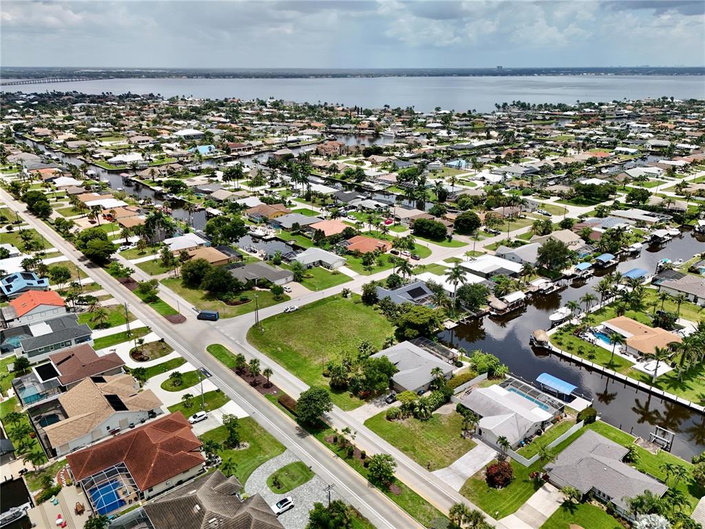 An aerial view shows a residential neighborhood with houses, canals, and a large body of water — 2014 EVEREST PARKWAY, CAPE CORAL, FL