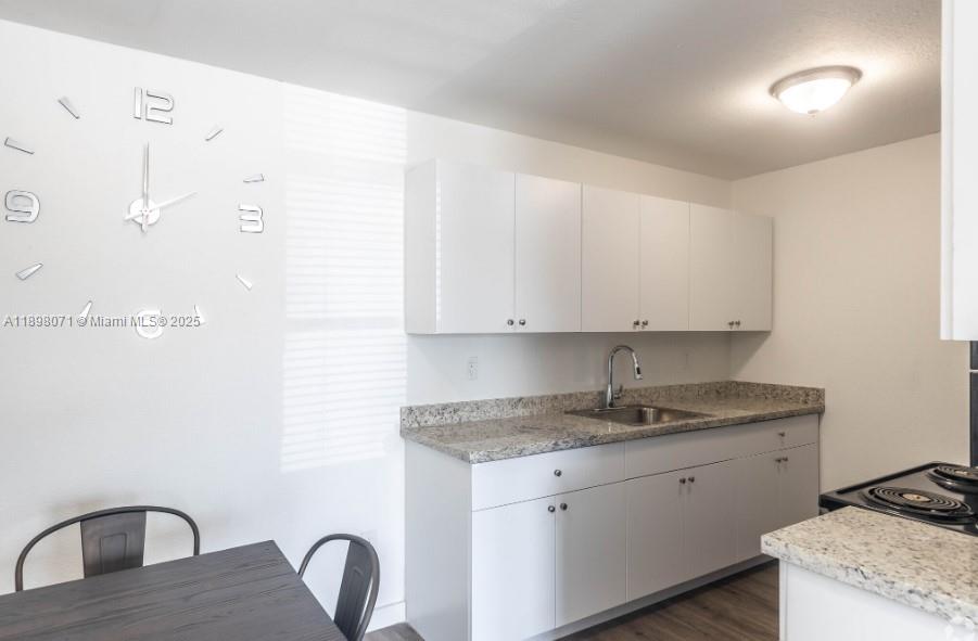 A kitchen features white cabinets, granite countertops, a stainless steel sink, and a wall clock — 2000 S Main Street # 000, Belle Glade FL 33430, BELLE GLADE, FL