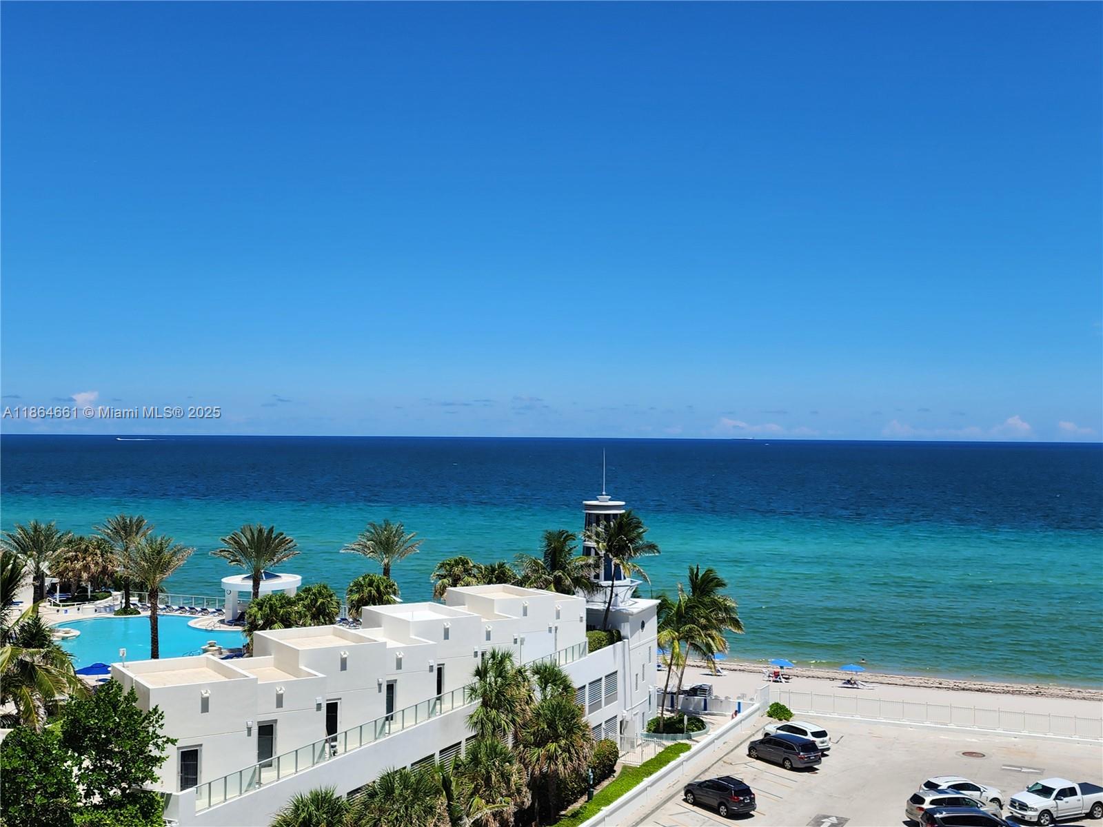 An aerial view shows a white building with a pool, palm trees, and the ocean — 3505 S Ocean Dr # 707, Hollywood FL 33019, HOLLYWOOD, FL
