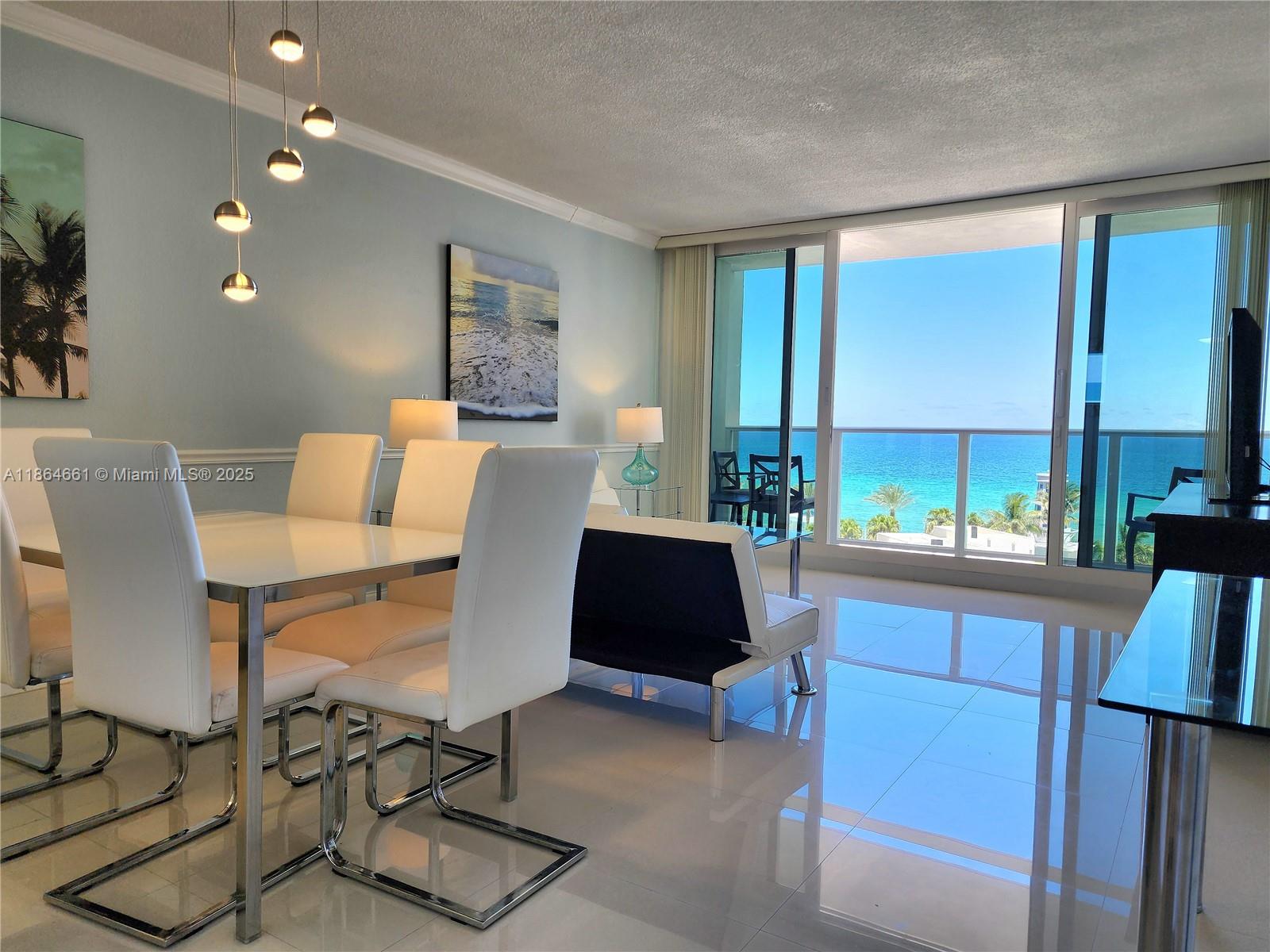 A dining area with white chairs and a glass table overlooks the ocean through windows — 3505 S Ocean Dr # 707, Hollywood FL 33019, HOLLYWOOD, FL