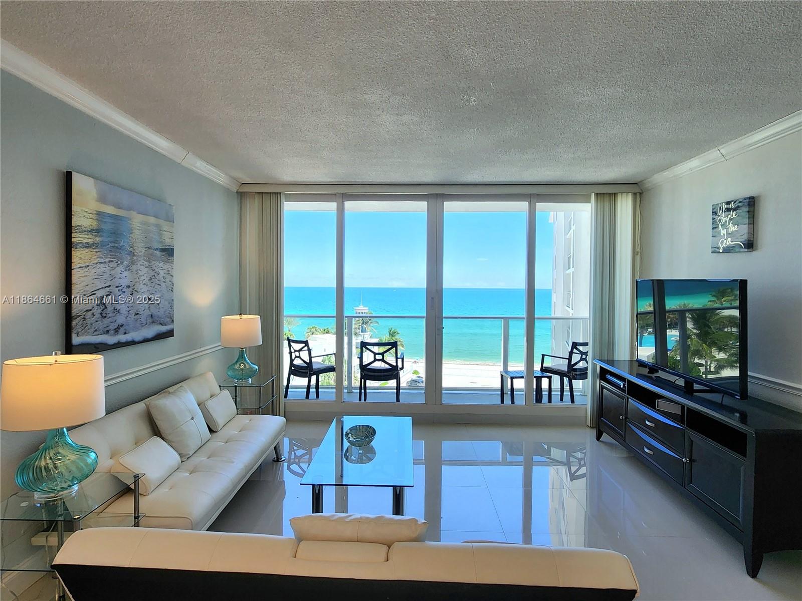 A living room with white tile floors, a white sofa, and a balcony overlooking the ocean — 3505 S Ocean Dr # 707, Hollywood FL 33019, HOLLYWOOD, FL