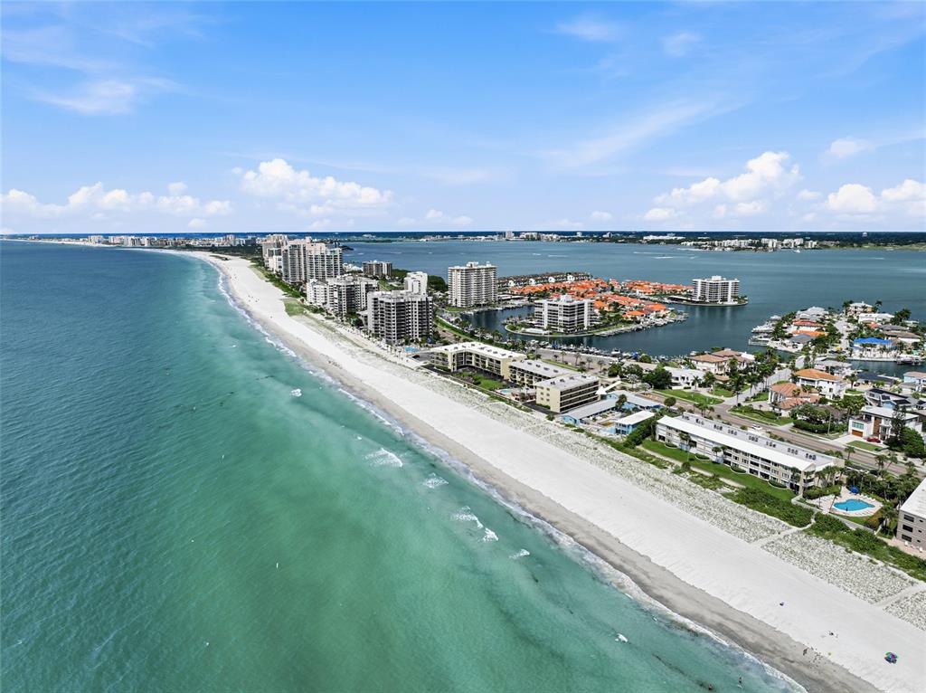 An aerial view of a coastal beach with multi-story apartment buildings and a bay — 3500 GULF BOULEVARD UNIT 204, BELLEAIR BEACH, FL