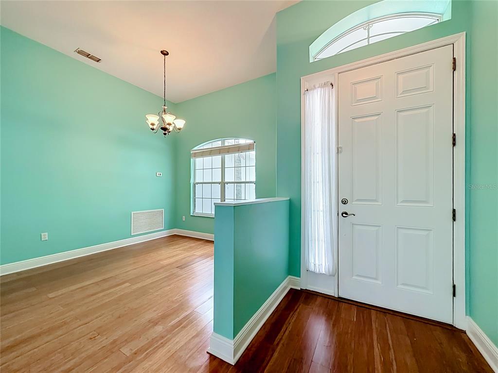 An entryway with a white front door leads into a dining room with turquoise walls — 2947 MAJESTIC ISLE DRIVE, CLERMONT, FL