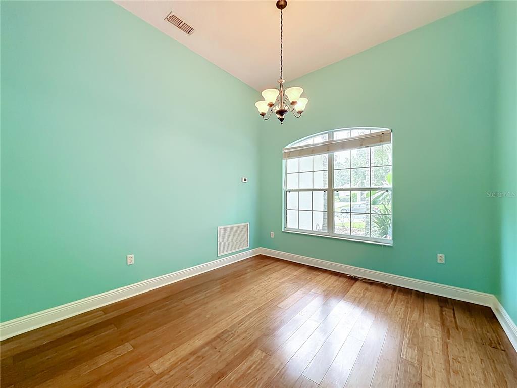 A dining room with light green walls, hardwood floors, a chandelier, and an arched window — 2947 MAJESTIC ISLE DRIVE, CLERMONT, FL
