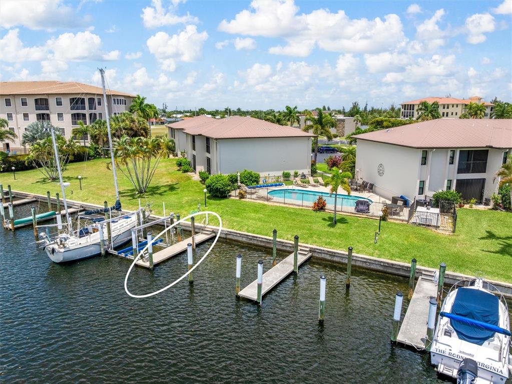 An aerial view shows a waterfront property with boat slips, a swimming pool, and buildings — 3221 WHITE IBIS COURT UNIT C1, PUNTA GORDA, FL