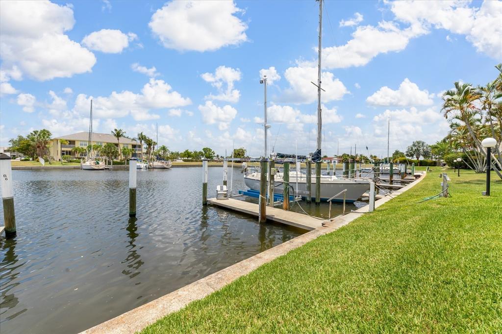 A canal view features a sailboat docked at a pier beside a grassy lawn — 3221 WHITE IBIS COURT UNIT C1, PUNTA GORDA, FL