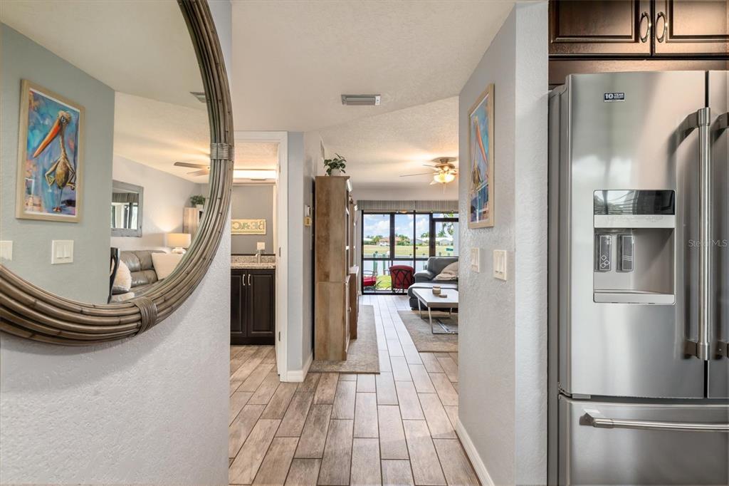 A hallway with wood-look tile flooring leads to a living area overlooking a canal — 3221 WHITE IBIS COURT UNIT C1, PUNTA GORDA, FL