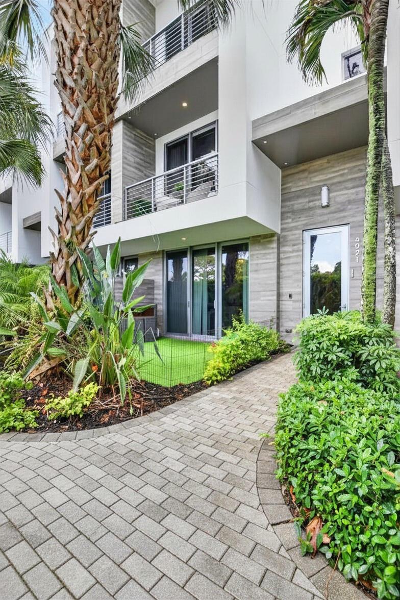 A modern multi-story building exterior features a paved walkway, landscaping, and a small fenced patio — 4021 NW 18th Way, Boca Raton FL 33431, BOCA RATON, FL