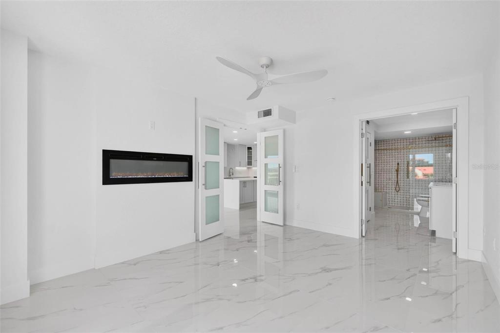 A bright room with white marble floors, a wall-mounted fireplace, and double doors leading elsewhere — 4900 BRITTANY DRIVE S UNIT 405, ST PETERSBURG, FL