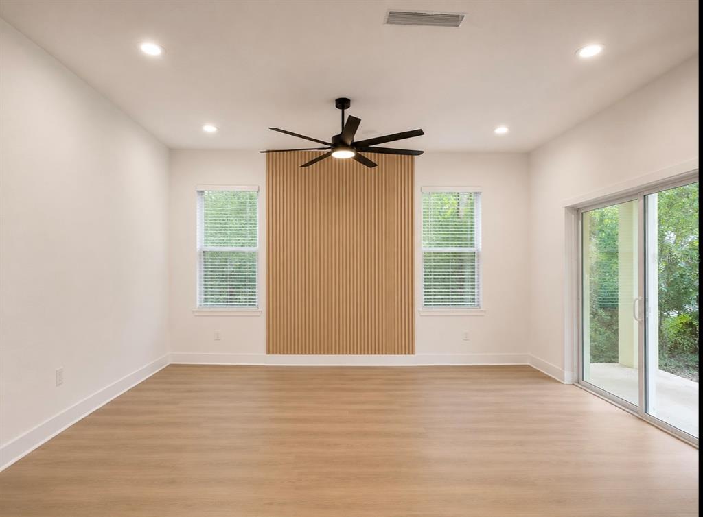 A living room features light wood-look flooring, a slatted wood accent wall, and sliding doors — 1064 MONROE AVENUE, BROOKSVILLE, FL