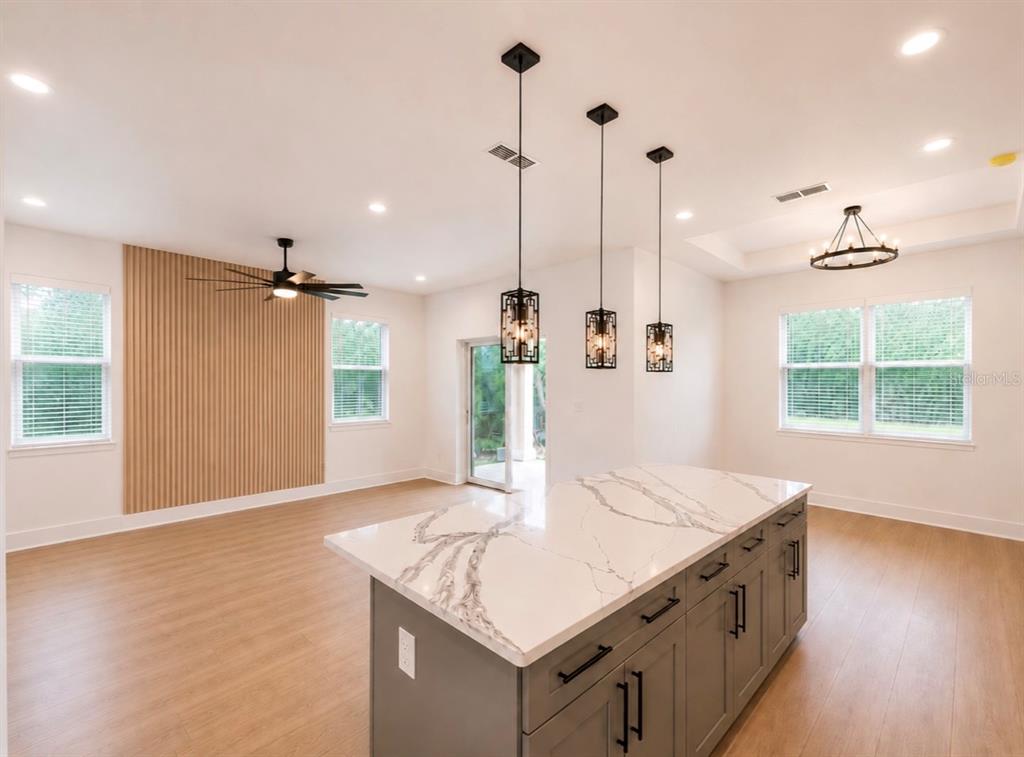 A kitchen island with a marble countertop sits in a room featuring wood-slat wall paneling — 1064 MONROE AVENUE, BROOKSVILLE, FL