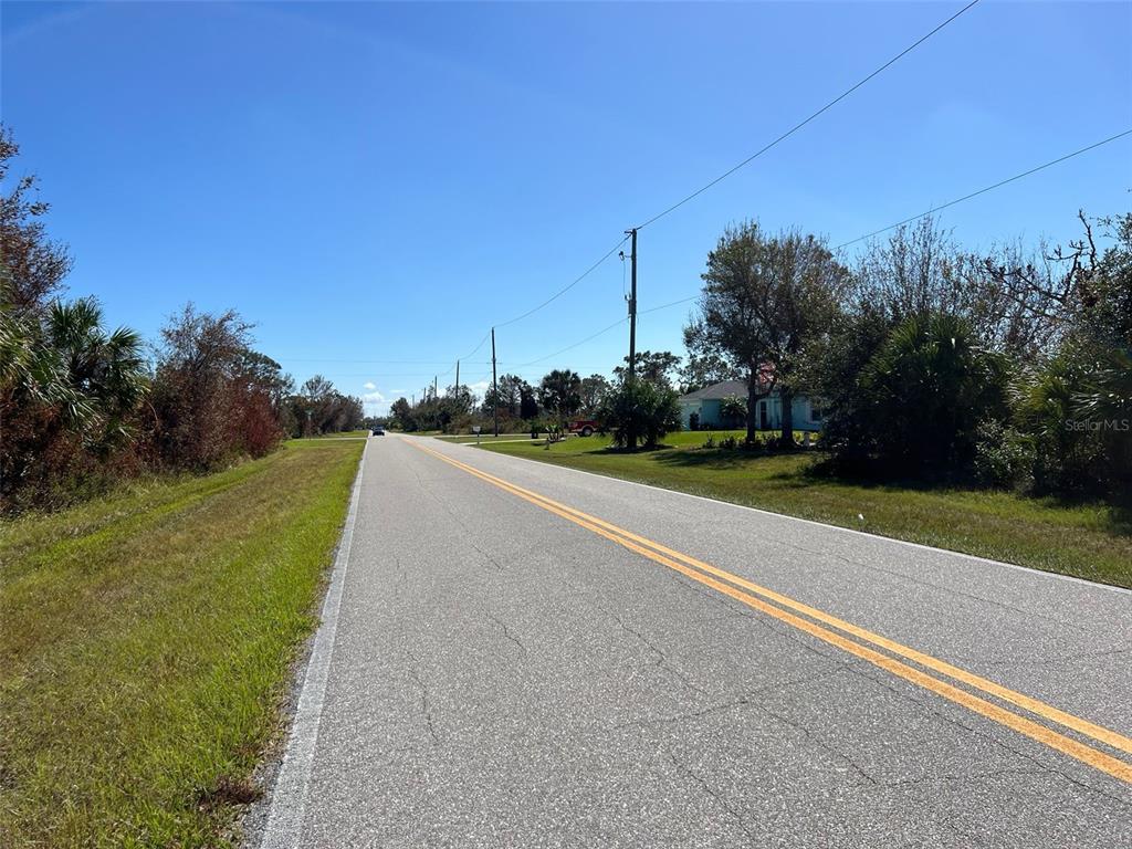 A paved road with double yellow lines stretches through a rural area with trees — 13224 MARATHON BOULEVARD, PORT CHARLOTTE, FL