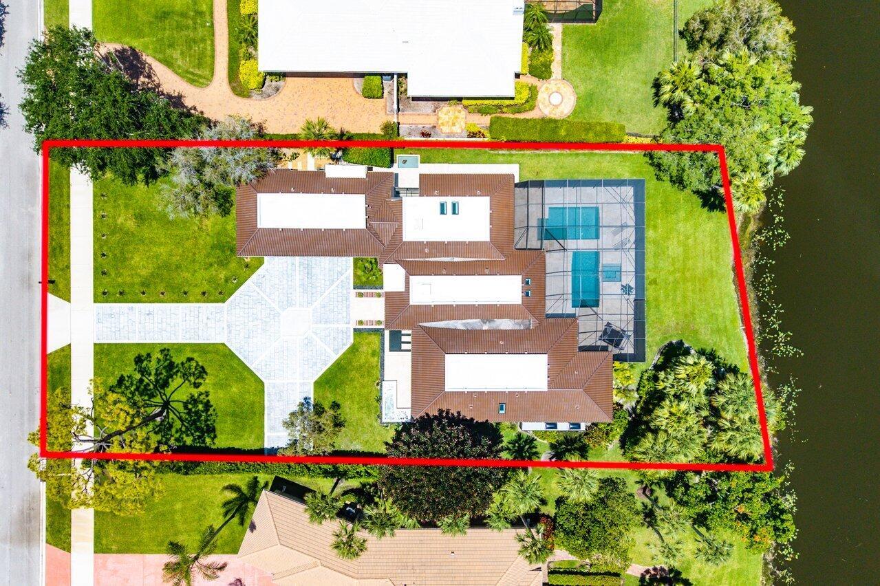 An aerial view shows a house with a tiled roof, pool, and large paved driveway — 1648 Breakers West Boulevard, West Palm Beach FL 33411, WEST PALM BEACH, FL