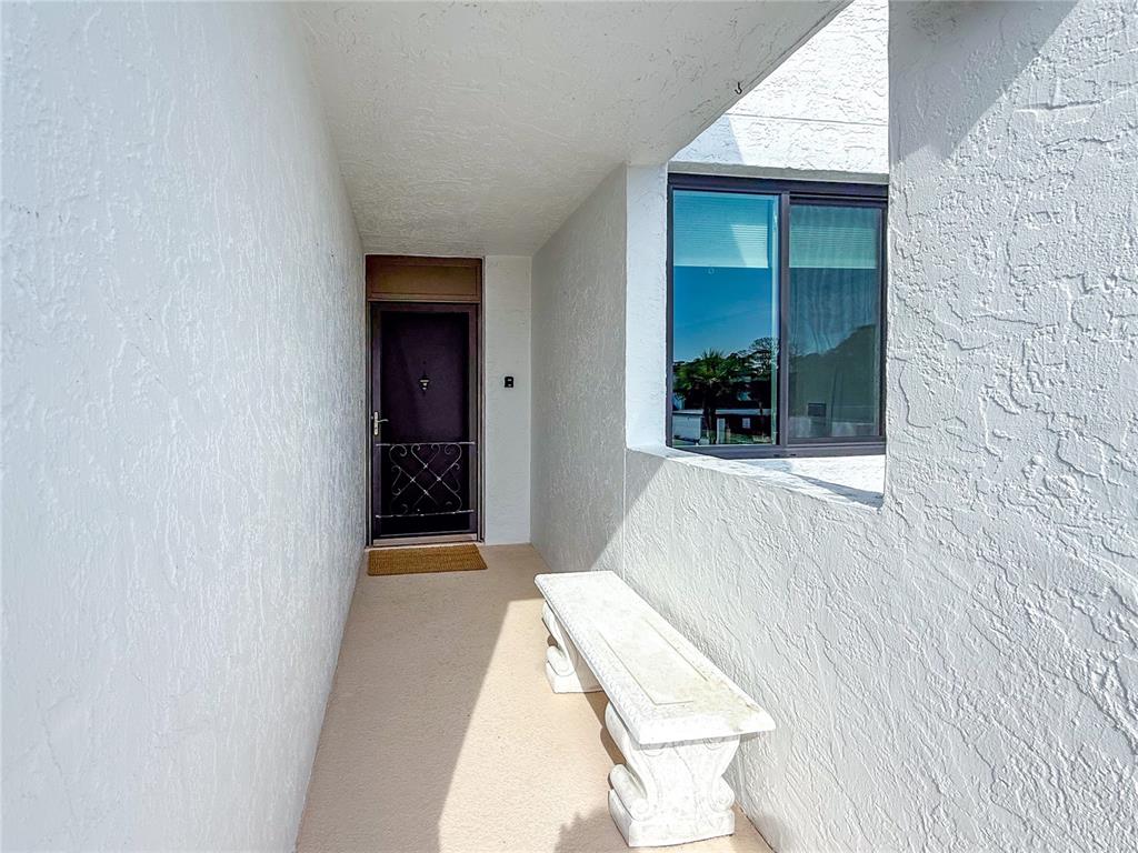 A covered entryway features a white stone bench, a dark door, and a window — 724 BAYPORT WAY UNIT 724, LONGBOAT KEY, FL