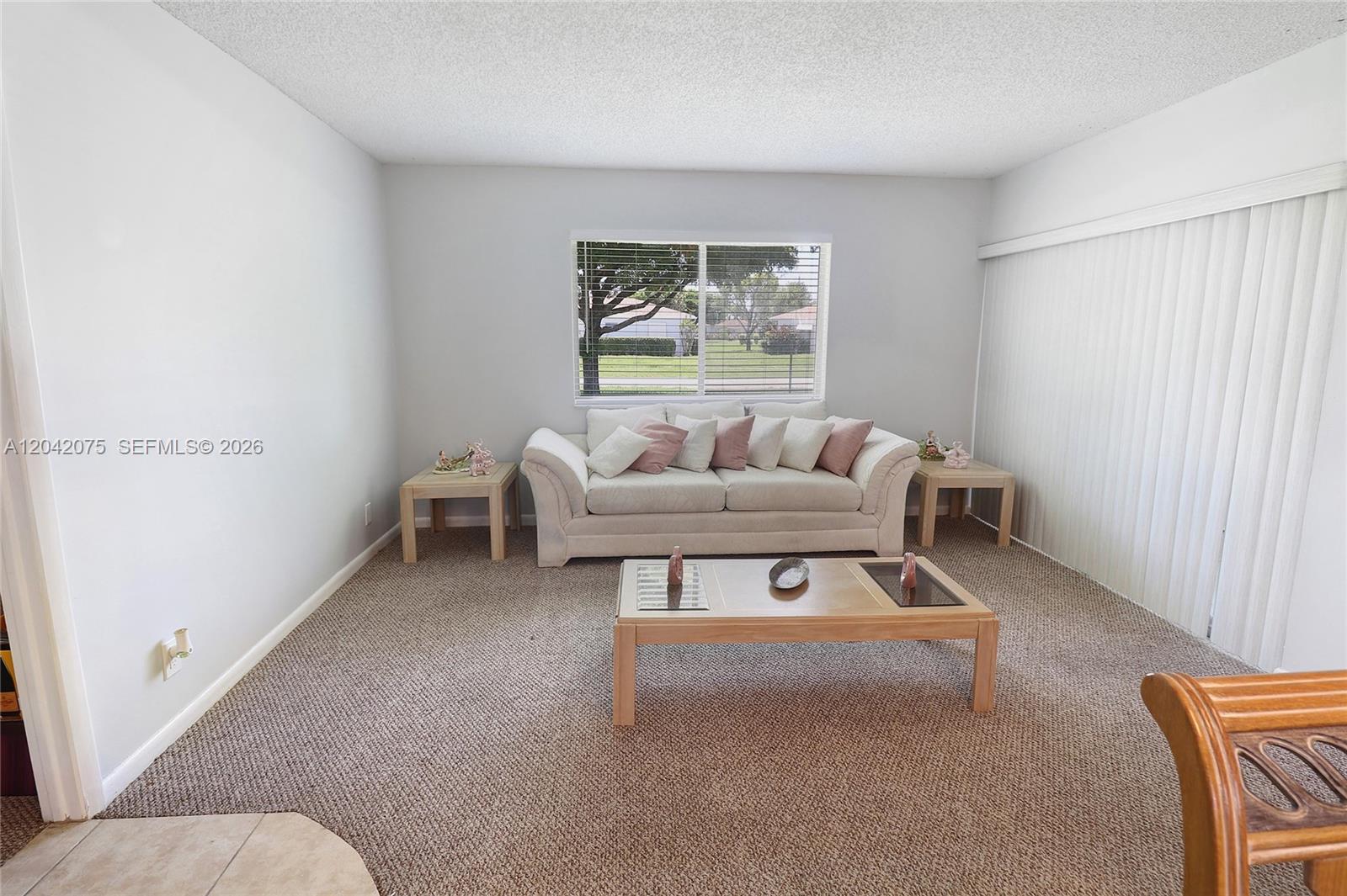 A living room features a beige sofa, a wooden coffee table, and carpeted floors — 14771 Wildflower Ln, Delray Beach FL 33446, DELRAY BEACH, FL